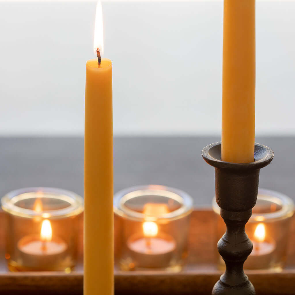 Raw beeswax taper candle burning beside tea lights, Bluecorn Candles product lifestyle shot