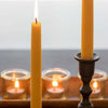 Raw beeswax taper candle burning beside tea lights, Bluecorn Candles product lifestyle shot