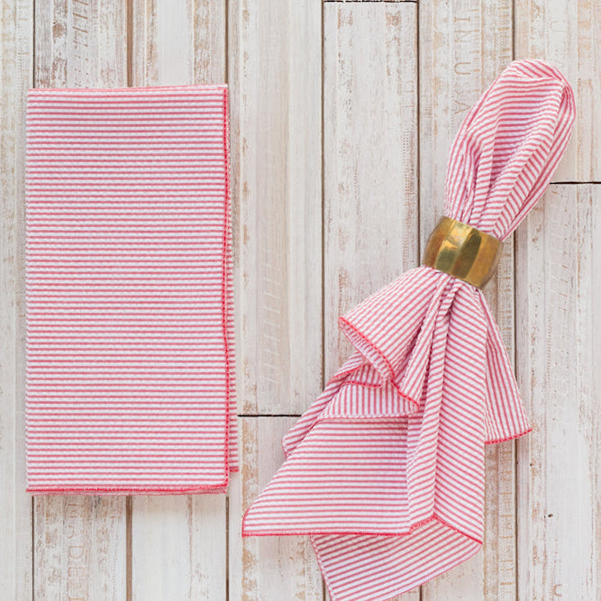 Red seersucker cloth napkins folded and displayed on a wooden table