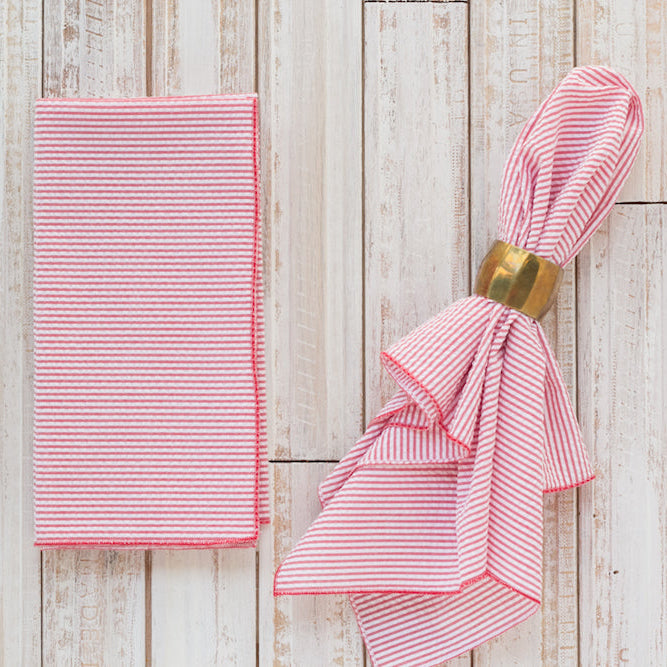 Red seersucker reusable dinner napkins folded on a wooden table