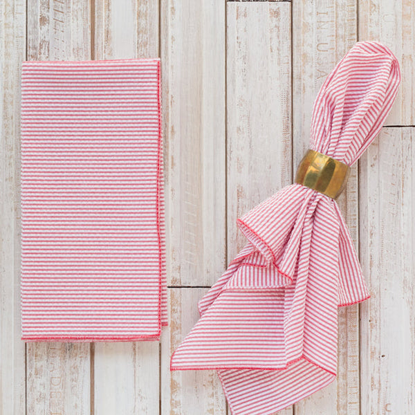Red seersucker reusable dinner napkins folded on a wooden table