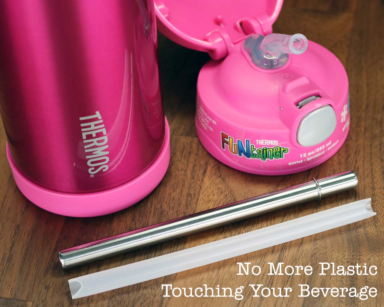 Pink Thermos with straw and lid on a wooden surface