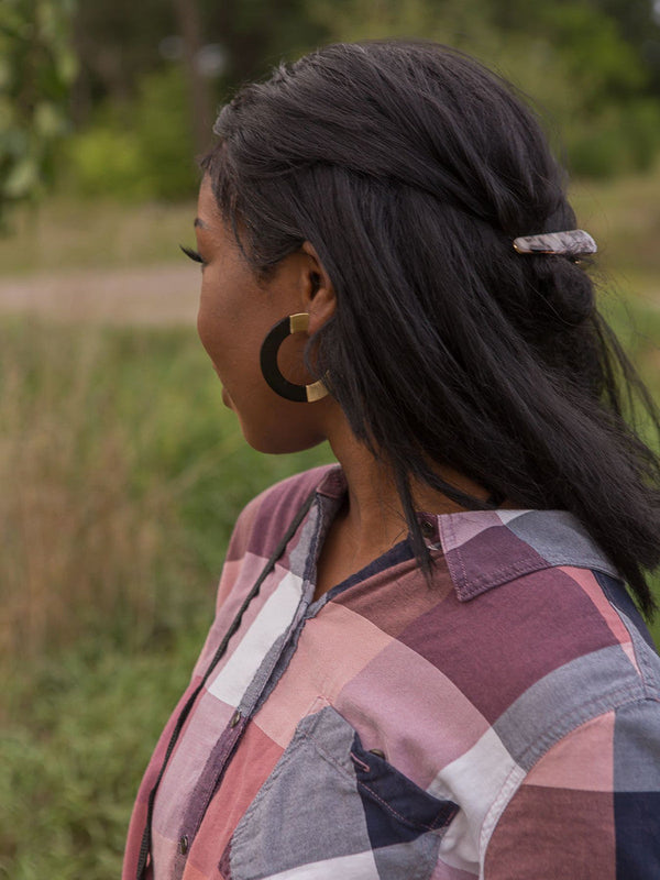 Close-up of large retro horn and brass hoop earrings handcrafted by women artisans in India