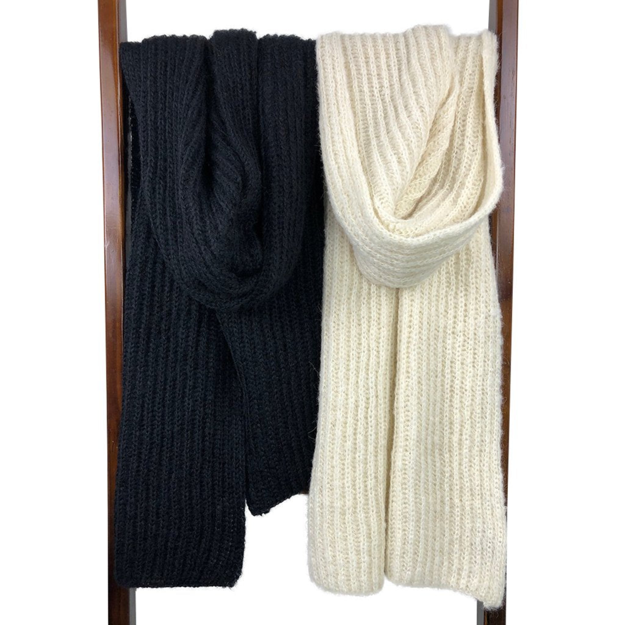 Black and white knitted scarves on a wooden rack against a white background