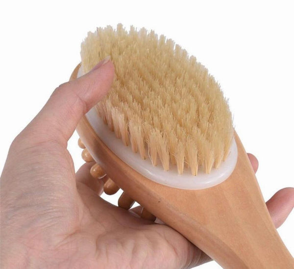 Hand holding a wooden brush with bristles against a white background