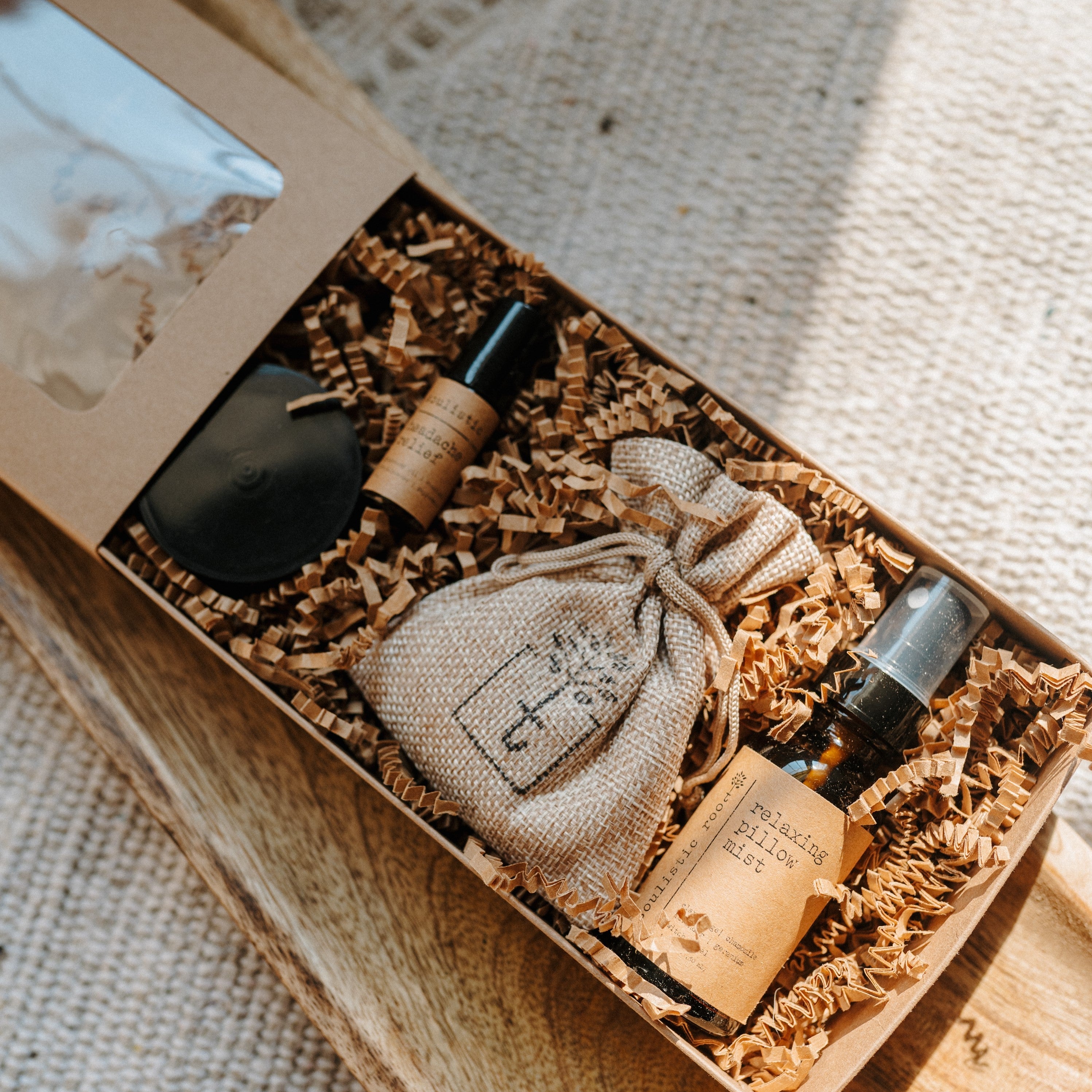Set of skincare products including bottles and a pouch in a box on a textured fabric background