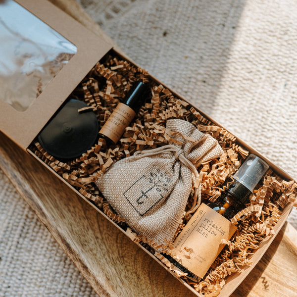 Set of skincare products including bottles and a pouch in a box on a textured fabric background