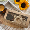 Gift box with heart-shaped item, candle, and sunflowers on a wooden surface