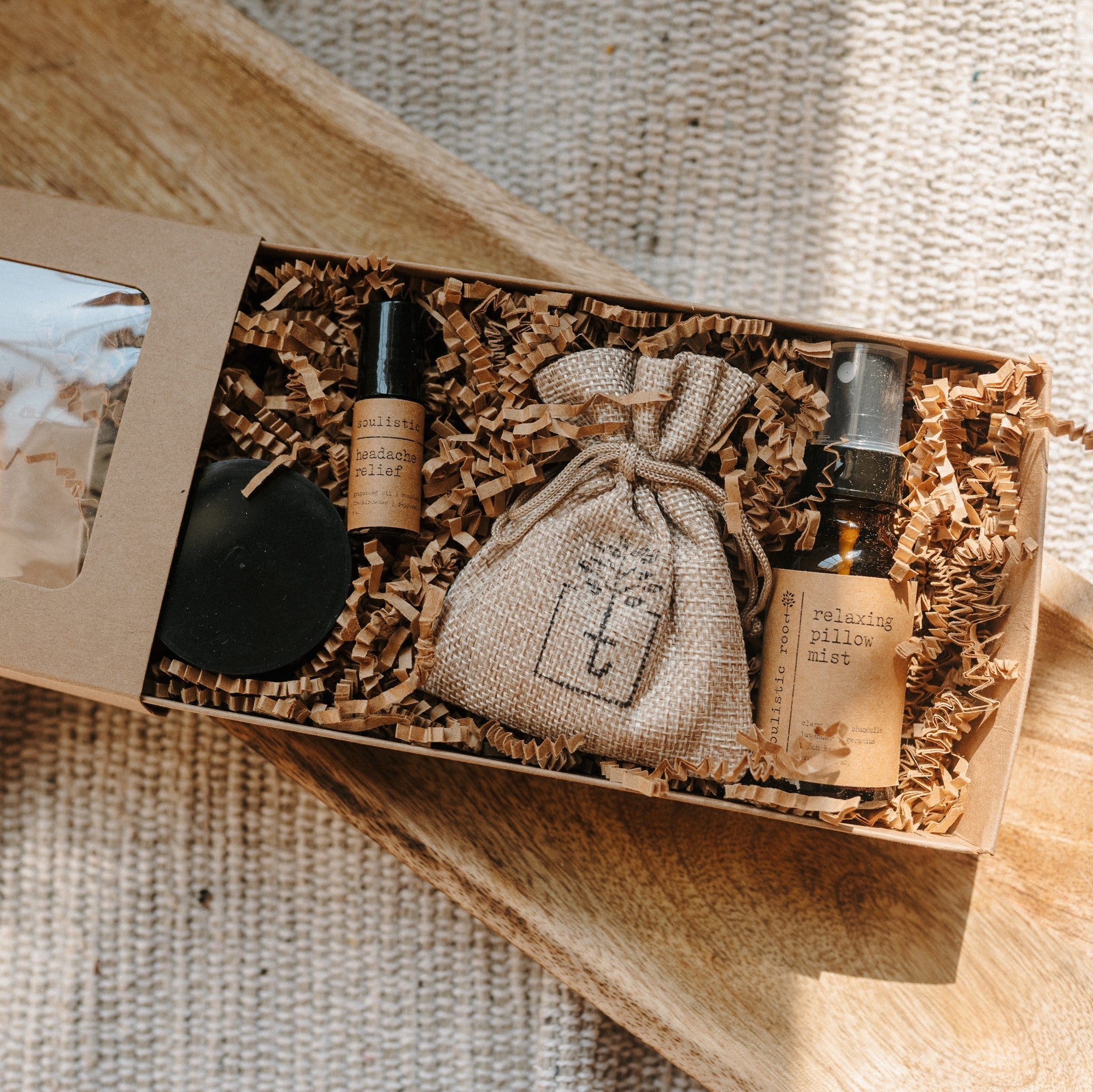Gift set with bottles and a pouch in a wooden box on a textured surface