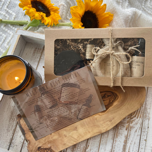 Gift set with sunflowers, candle, and card on a wooden surface