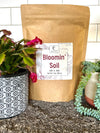 Bag of Bloomin' Soil with potted plants on a neutral background