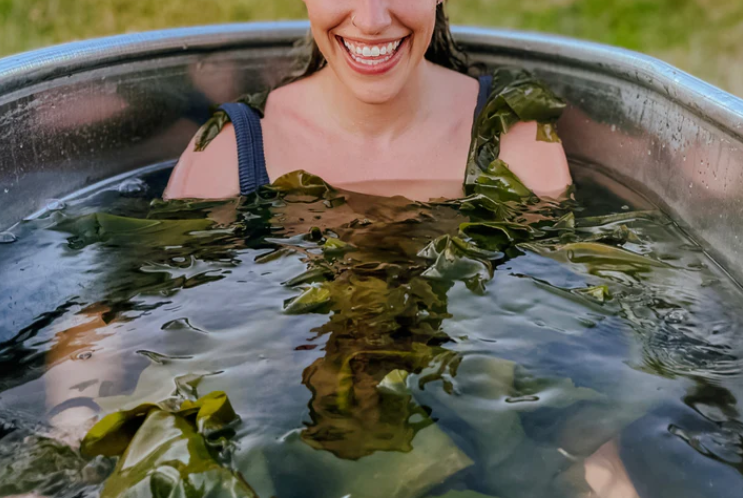 Woman soaking in a bath with seaweed bath soak. Description: This image shows a woman soaking in a bath with seaweed bath soak. The seaweed bath soak is made with nutrient-dense sea kelp and solar-dried Maine sea salt. It is a natural way to detoxify the body, relieve dry skin, and alleviate sore muscles.