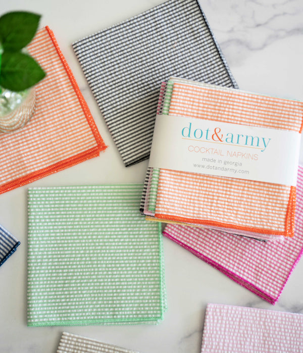 Seersucker cocktail napkins in multiple colors arranged on a surface, showing the 10-inch size perfect for entertaining