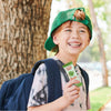 Child wearing a green cap and holding a Sunkist juice box outdoors.
