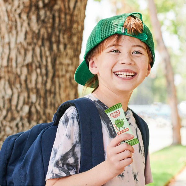 Child wearing a green cap and holding a Sunkist juice box outdoors.