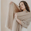 Woman holding a beige cashmere shawl against a neutral background