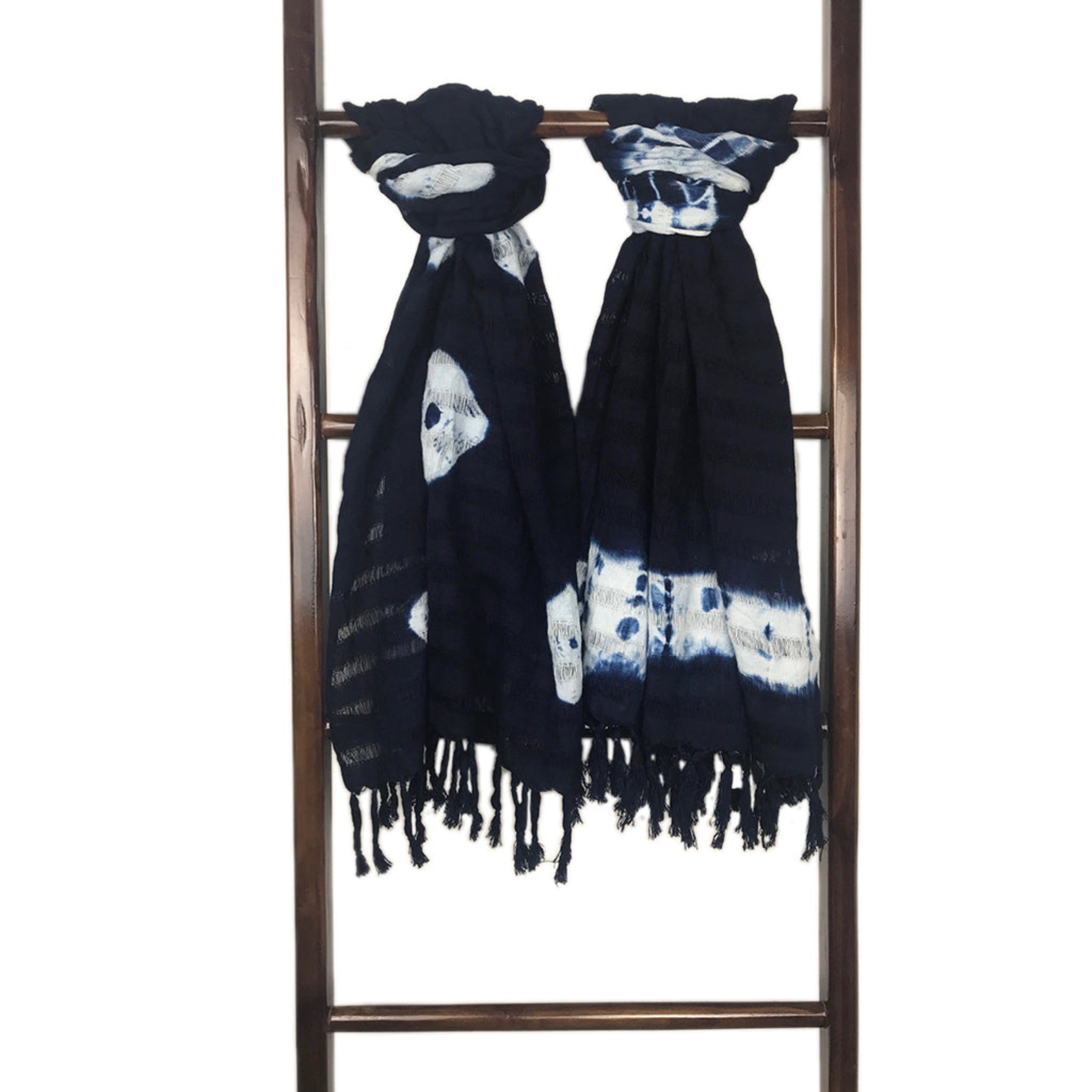 Black and white patterned scarf with fringe on a wooden ladder against a white background