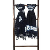 Black and white patterned scarf with fringe on a wooden ladder against a white background