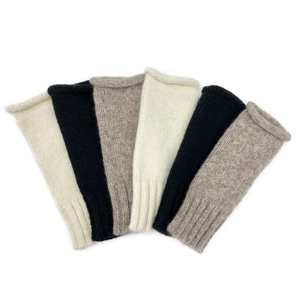 Set of four folded knitted arm warmers in black, beige, and gray on a white background. Shop the Snow Essential Knit Alpaca Gloves at Clozist. Handcrafted in Peru from eco-friendly Baby Alpaca fiber, these luxury fingerless gloves combine royal softness with modern functionality. The perfect sustainable gift for warmth and style. Shop the green Amazon alternative!