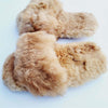 Pair of fluffy brown slippers on a light blue background