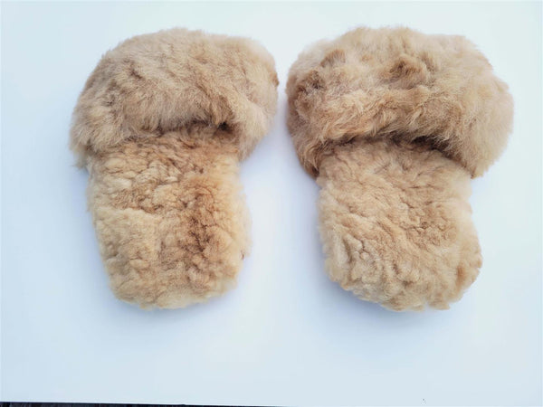 Pair of fluffy beige slippers on a light blue background