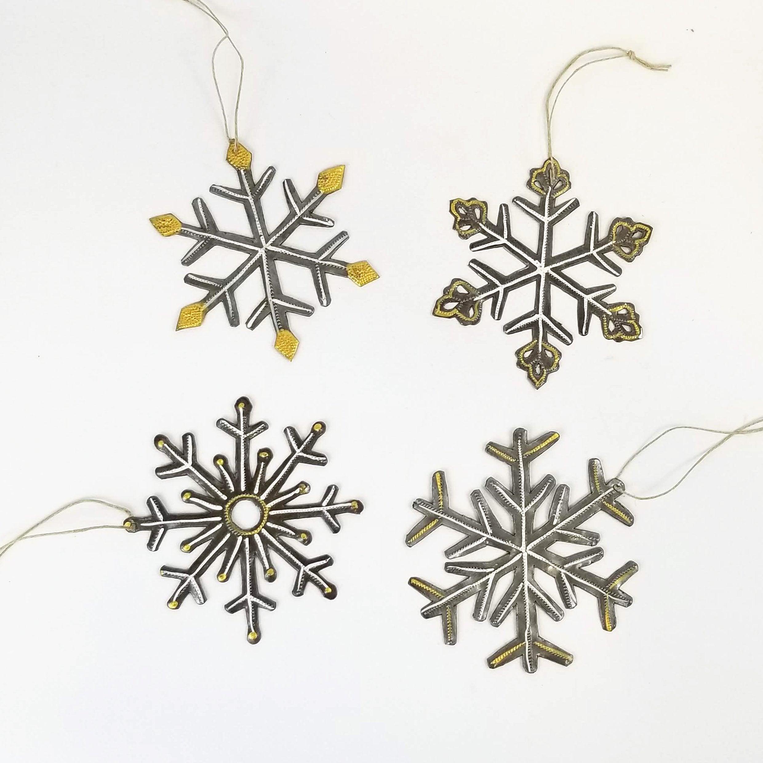 Four snowflake-shaped ornaments with gold and silver details on a white background