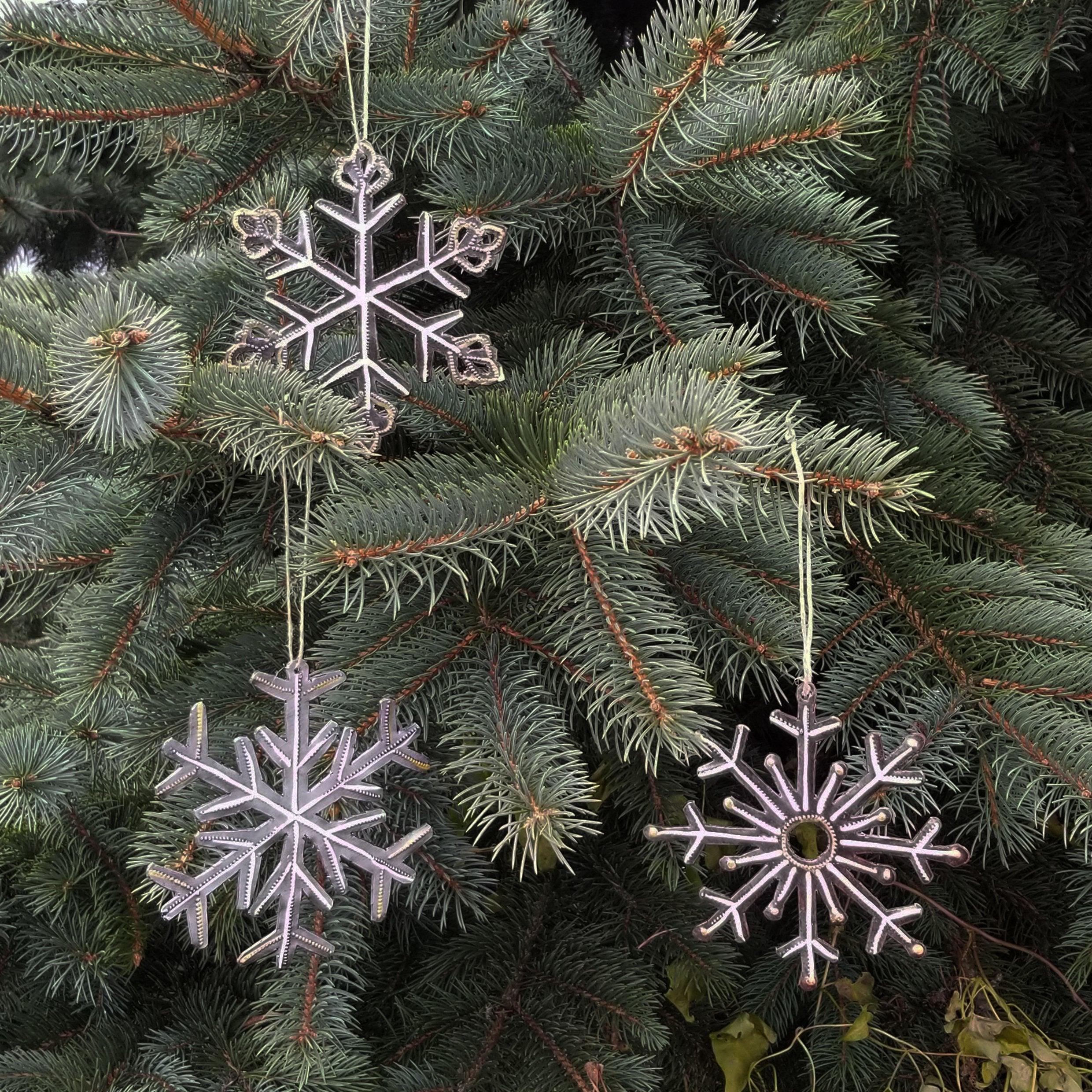 Decorative snowflake ornaments hanging on a Christmas tree.