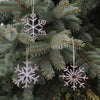 Decorative snowflake ornaments hanging on a Christmas tree.