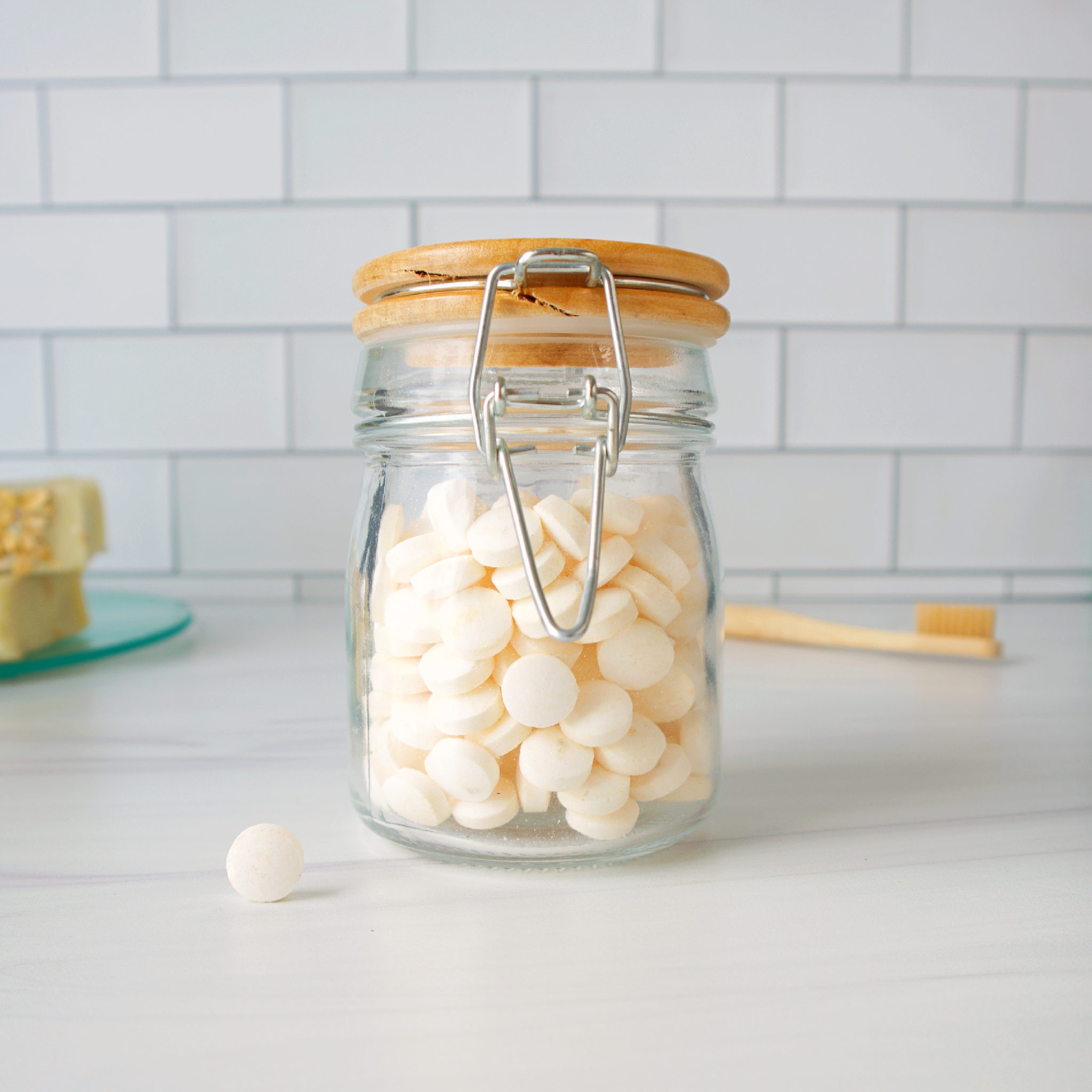 Glass jar with wooden lid filled with white round objects on a kitchen counter.
