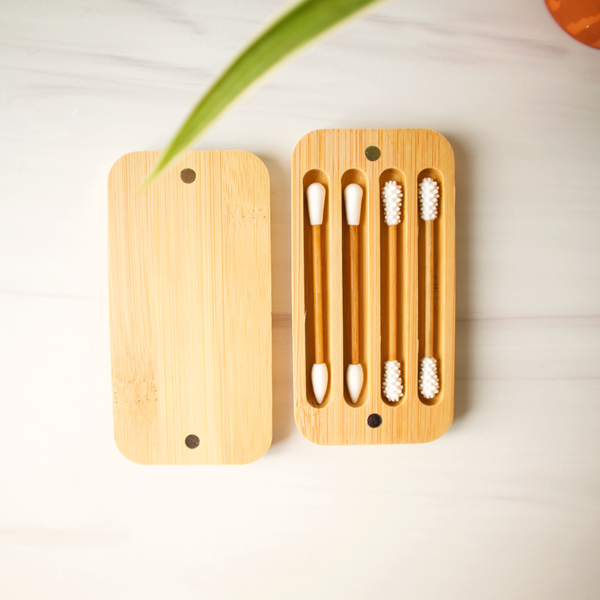 Set of four bamboo toothbrushes in a wooden holder on a light surface.