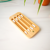 Bamboo toothbrush holder with multiple toothbrushes on a light surface.