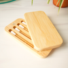 Set of bamboo toothbrushes in a wooden holder on a light surface.