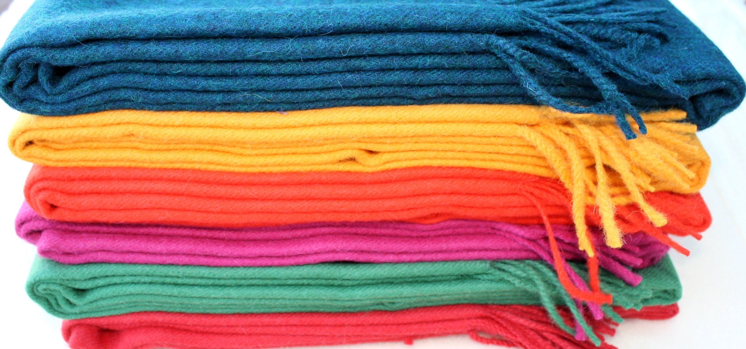 Stack of colorful folded cloths with tassels on a white background
