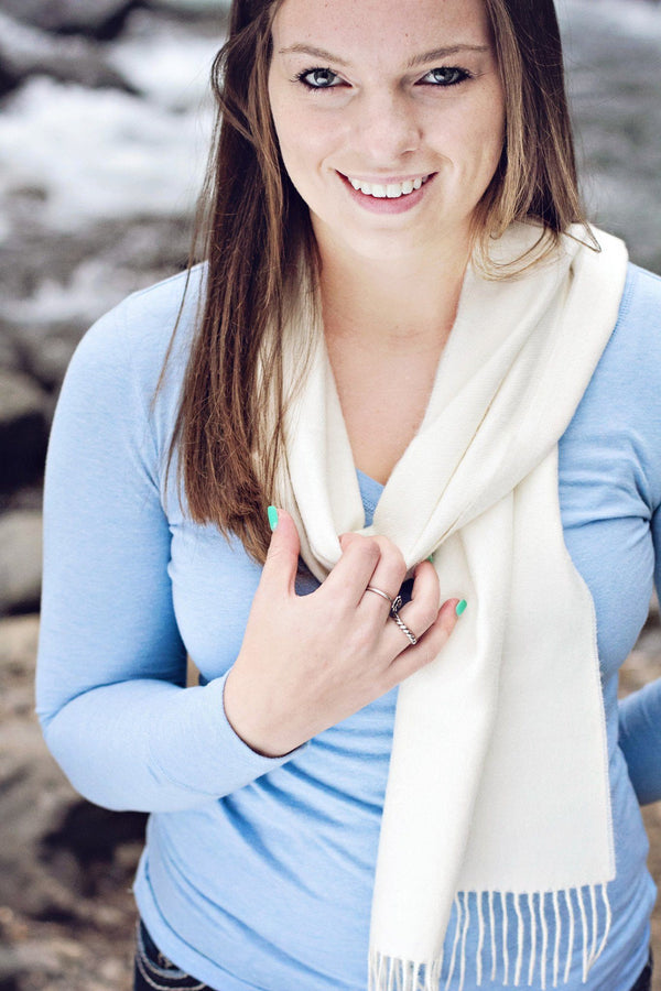 Woman wearing a light blue sweater and white scarf on a beach