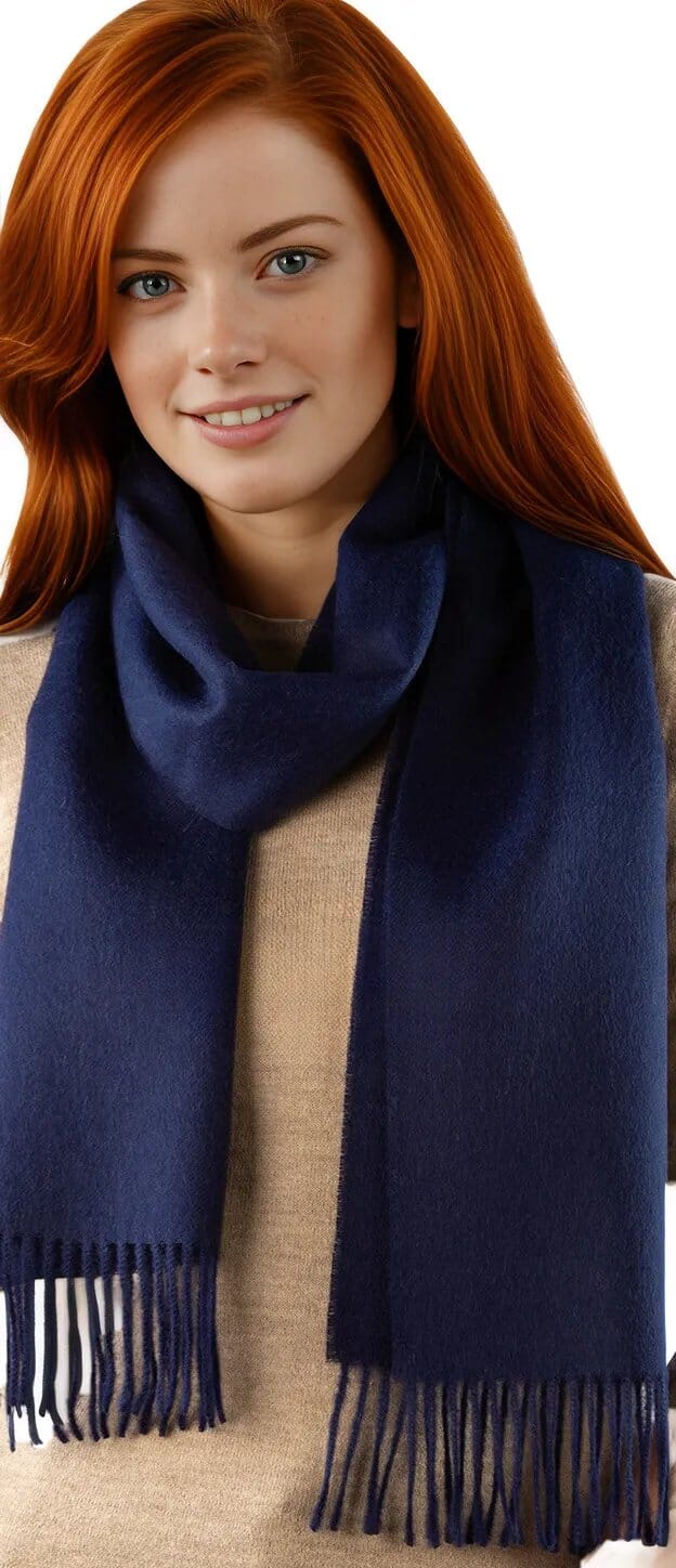 Woman wearing a navy blue scarf with fringes on a white background
