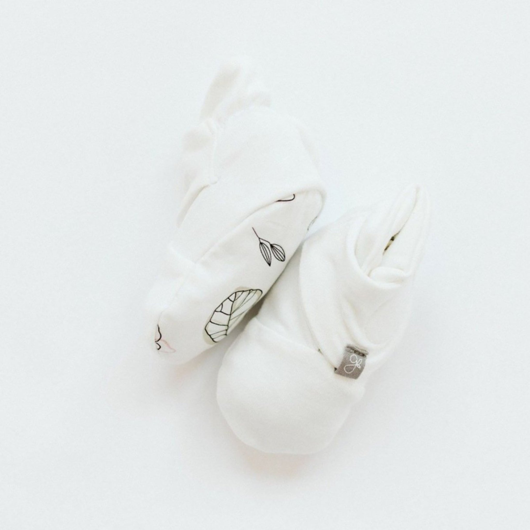 White baby rattle with leaf pattern on a light gray background
