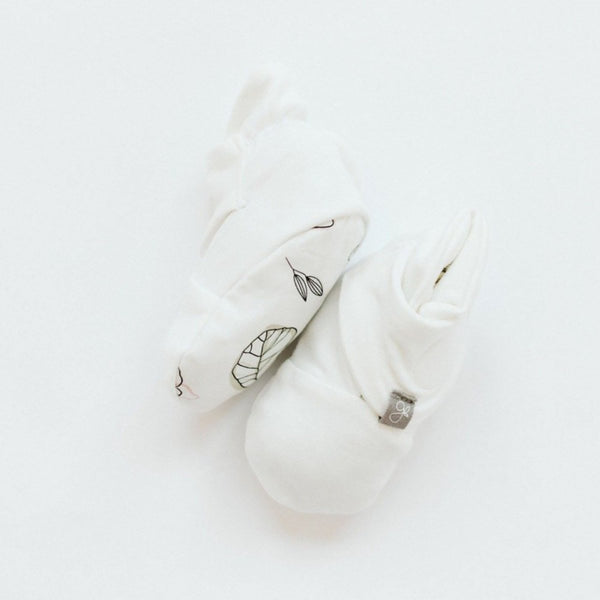White baby rattle with leaf pattern on a light gray background