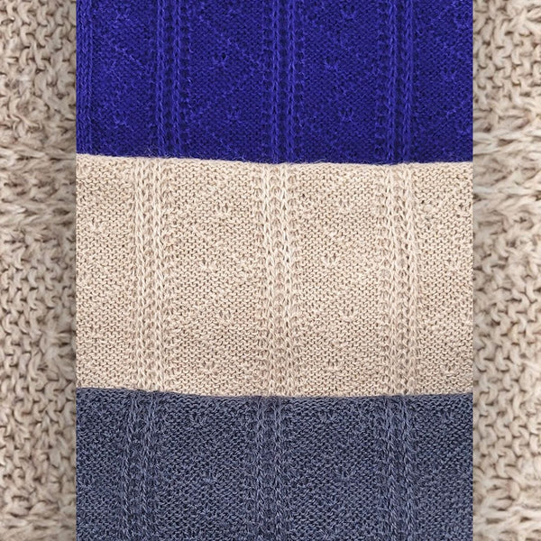 Close-up of a knitted fabric with blue, beige, and navy stripes on a textured background.