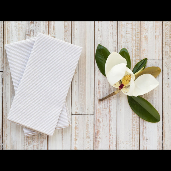 Tan seersucker cloth dinner napkins set of 4 on a white wooden table with magnolia accents