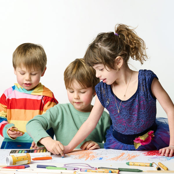 Three children engaged in a drawing activity with colorful crayons on a white background
