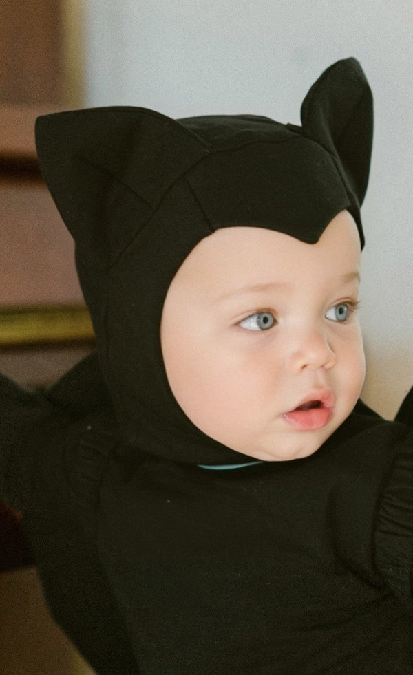 Baby wearing a black cat-themed costume with ears.