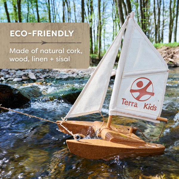 Eco-friendly toy sailboat with cork, wood, linen, and sisal materials, branded 'Terra Kids', on a natural setting.