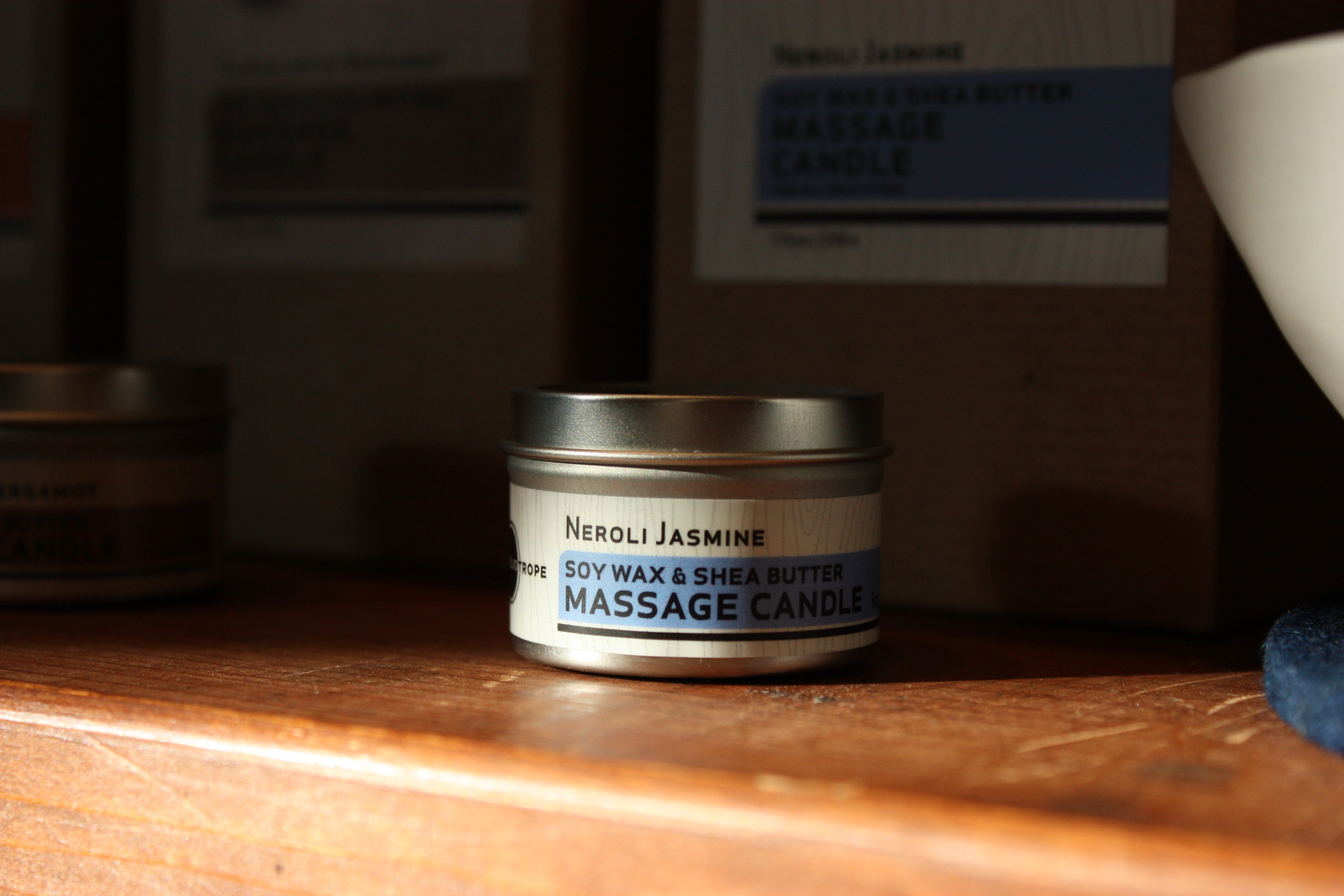 Neroli Jasmine massage candle on a wooden surface with a blurred background