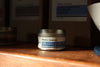 Neroli Jasmine massage candle on a wooden surface with a blurred background