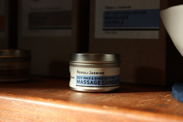 Neroli Jasmine massage candle on a wooden surface with a blurred background