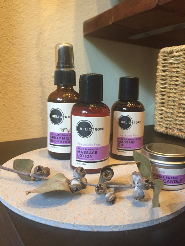 Flat lay of Heliotrope SF travel massage kit bottles and candle arranged on a clean surface, ready for travel