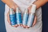 Full line of Plaine Products reusable travel size bottles laid out flat on a clean background