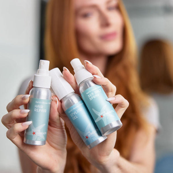Plaine Products travel styling set with gel, sea salt spray and hair repair bottles on a flat lay