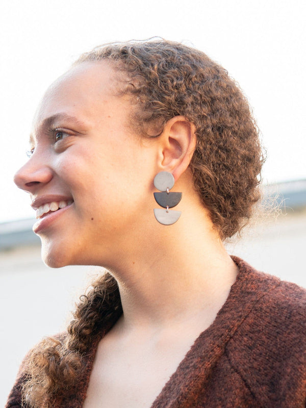 Close-up of black and grey half moon stacked earrings showing geometric design and plated metal findings