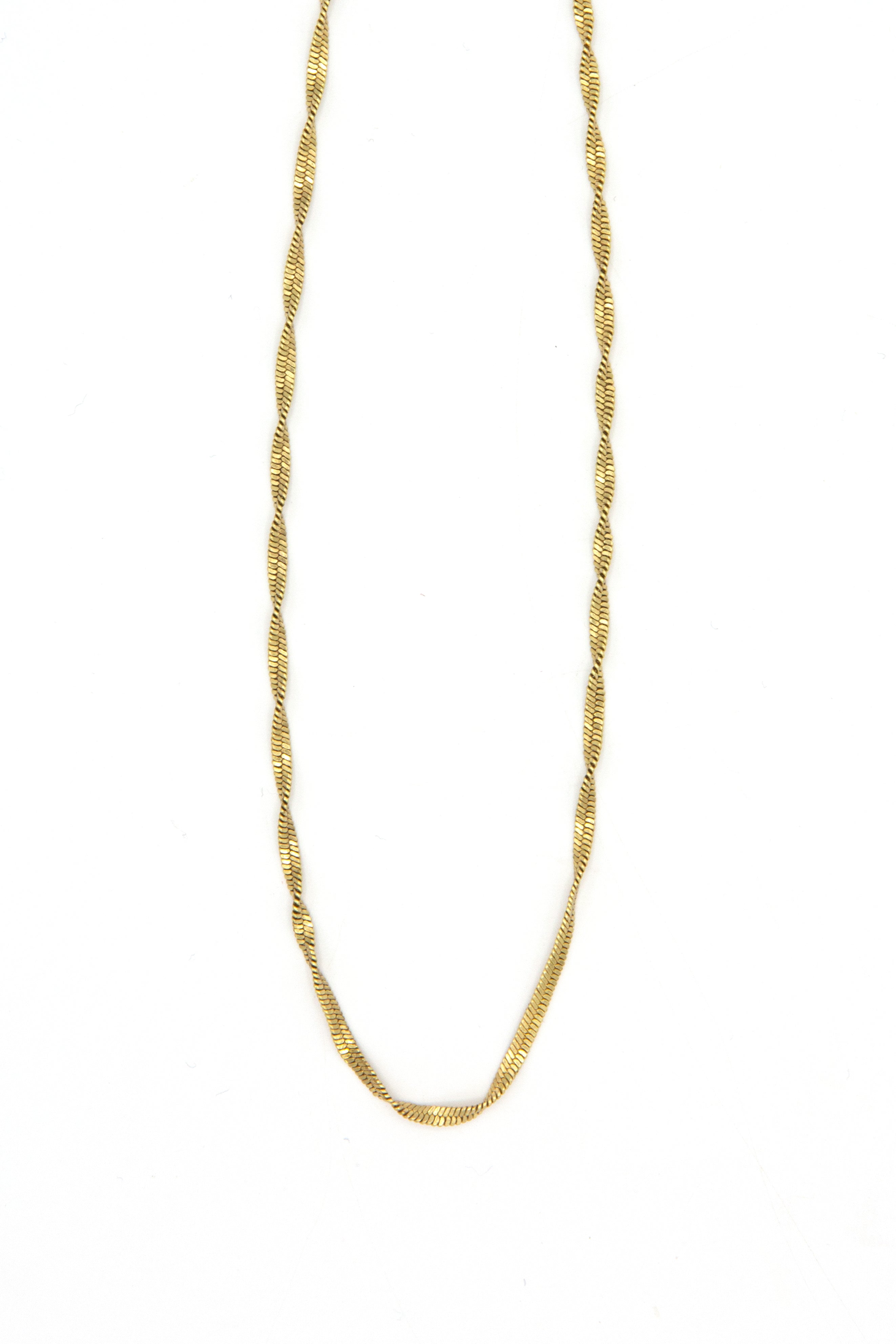 Flat lay of twisted snake chain necklace in gold and silver options on neutral background